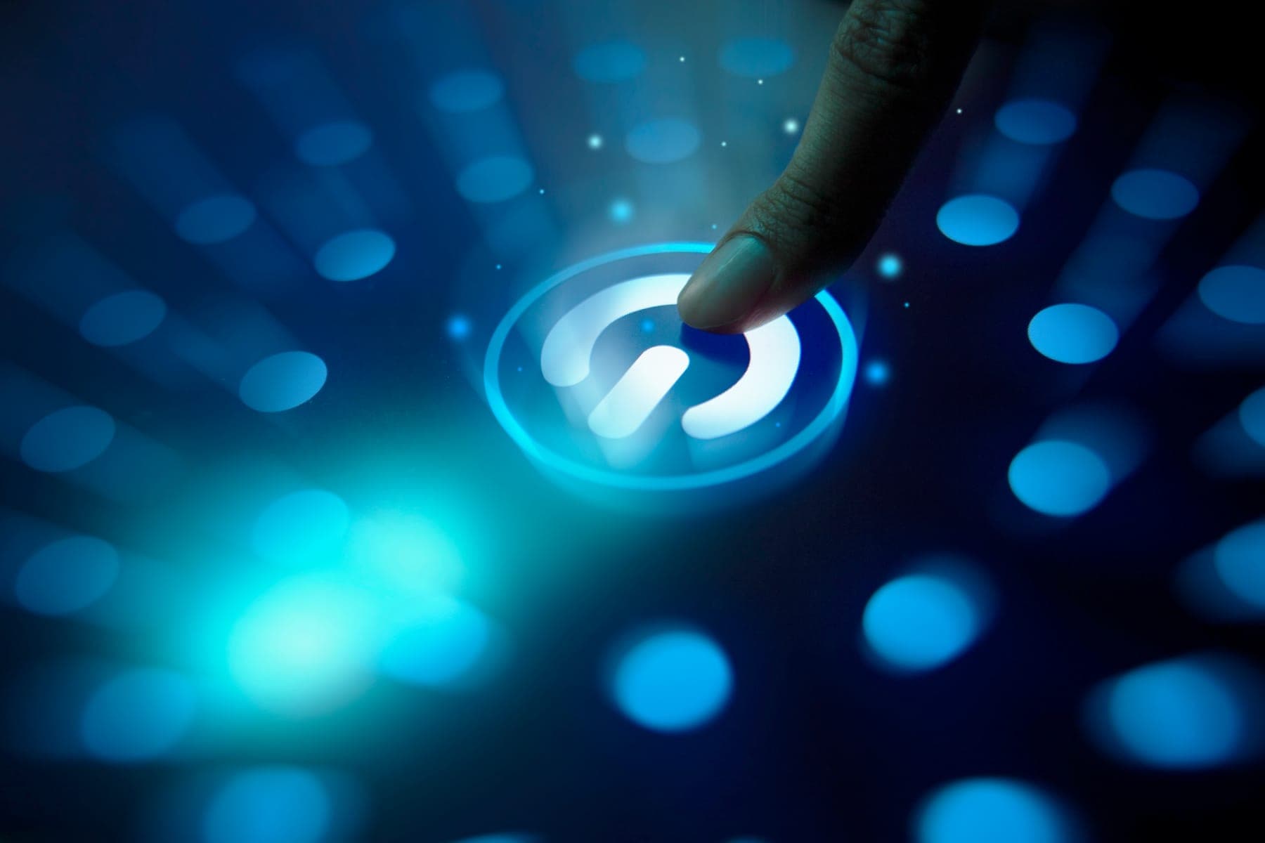 A finger pressing an illuminated power button