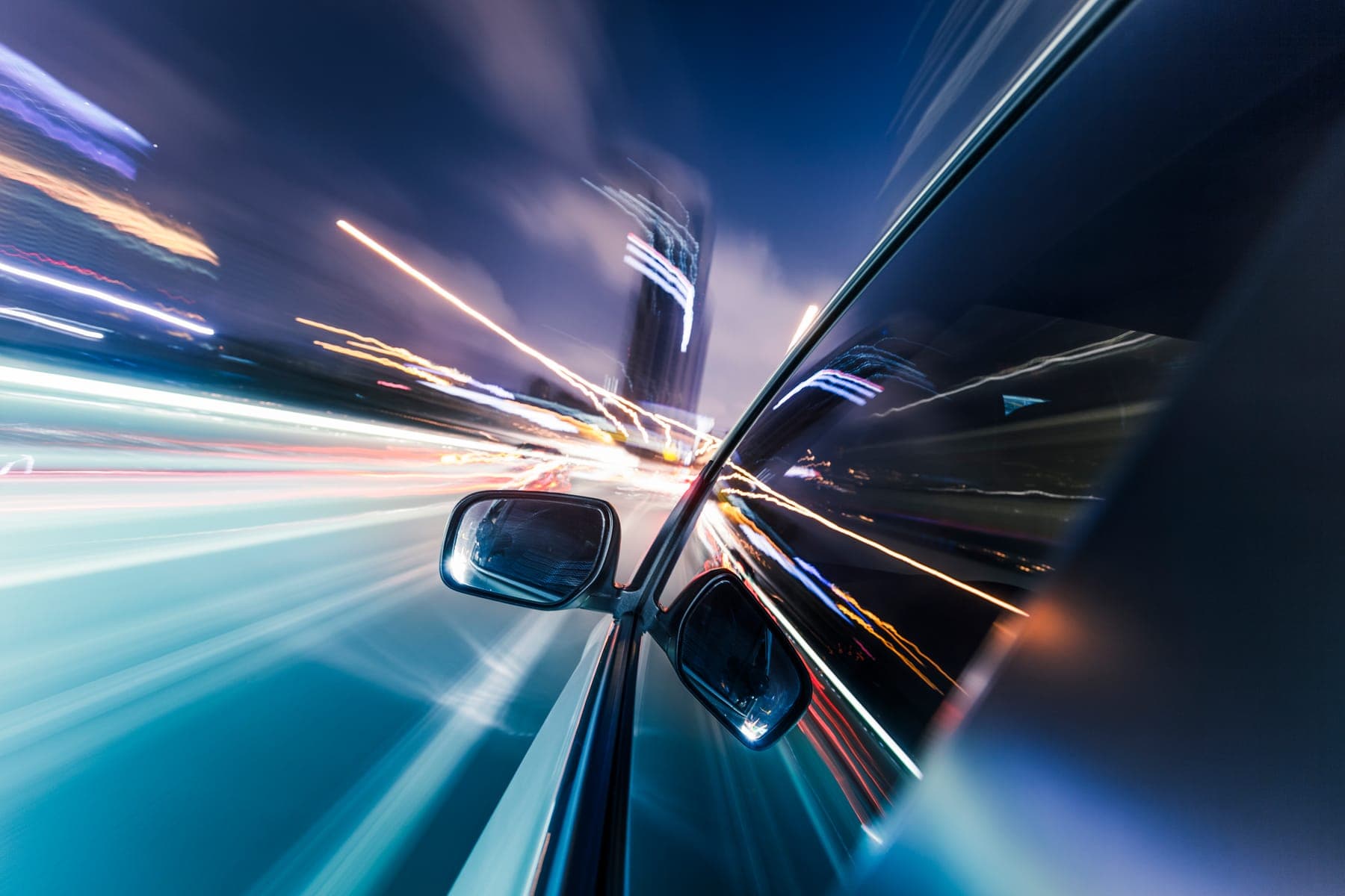 Light trails reflected along the side of a car in motion